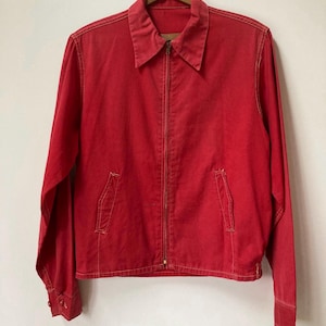 May include: A vibrant red jacket with a full zip, two front pockets, and a collared neckline. The long-sleeved jacket is suspended on a wooden hanger. The jacket is made of a solid red fabric.
