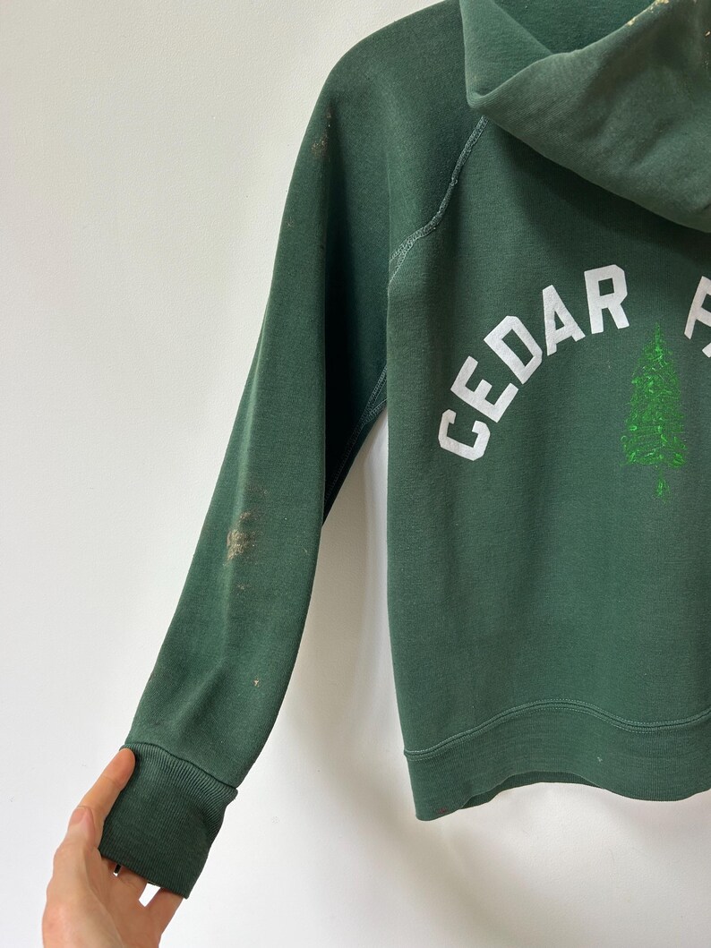 K&ouml;nnte beinhalten: Ein Set aus drei Keramikbechern mit gesprenkelter, cremefarbener Glasur. Jeder Becher zeigt ein handgemaltes Design: ein blau-gr&uuml;nes Blatt, eine gelbe Blume und eine rote Beere. Die Becher haben eine einfache, abgerundete Form und einen bequemen Griff.