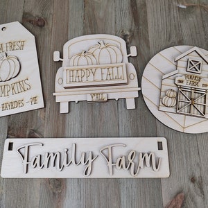 Puede incluir: Cuatro letreros de madera con temática otoñal. Los letreros muestran un camión con calabazas, un granero con el texto "Pumpkin Farm", una etiqueta con el texto "Farm Fresh Pumpkins Cider - Hayrides - Pie", y un letrero con el texto "Family Farm".