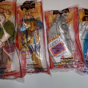 May include: Four plastic bags containing The Hunchback of Notre Dame character toys from Burger King. The characters are Quasimodo, Phoebus, Hugo, and Esmeralda. Each bag has a warning label that says "This bag is not a toy. Keep away from children. Please discard."