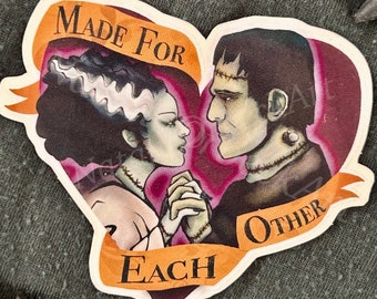 May include: A heart-shaped sticker with a couple of cartoon monsters. The woman has green skin and black hair with white streaks. The man has green skin and black hair. They are holding hands and looking at each other. The sticker says "Made for Each Other" in a banner.