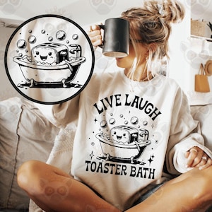 May include: A white sweatshirt with the text "Live Laugh Toaster Bath" and a black and white illustration of a toaster in a bathtub with bubbles.
