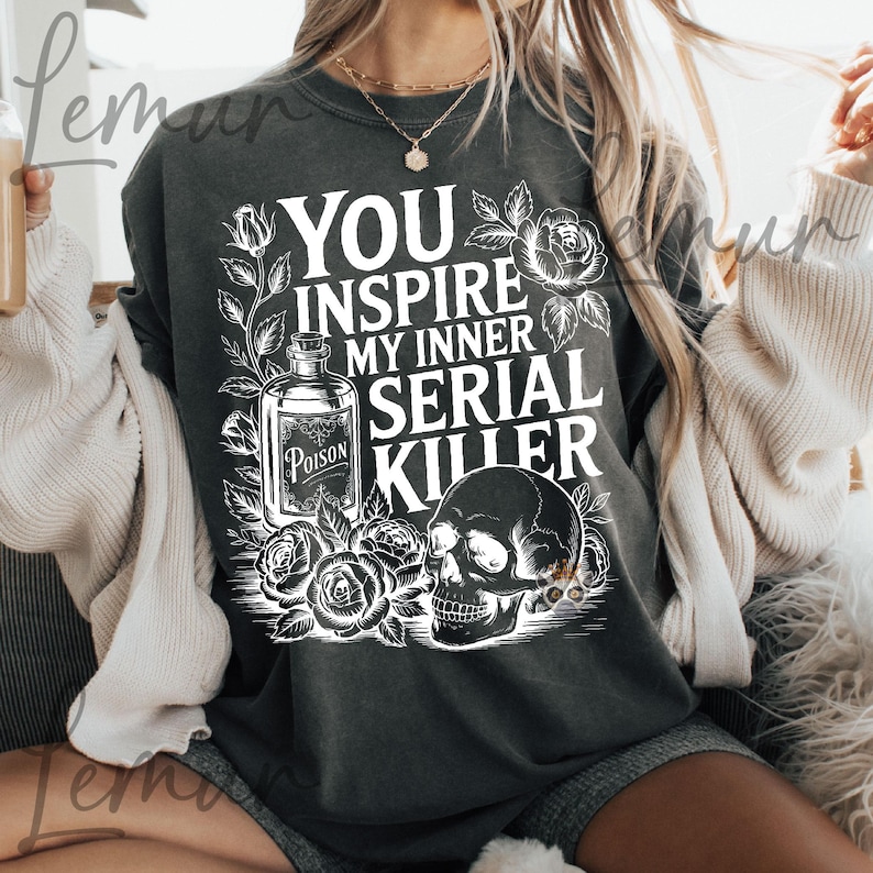 May include: Dark gray sweatshirt with the text "YOU INSPIRE MY INNER SERIAL KILLER" in white. The design includes a poison bottle, roses, and a skull. The sweatshirt is a comfortable, casual style.