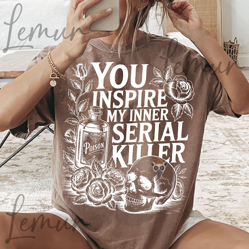 May include: Brown t-shirt with the text "YOU INSPIRE MY INNER SERIAL KILLER" in white. The graphic includes a poison bottle, roses, and a skull with an owl. The shirt has a crew neck and short sleeves.