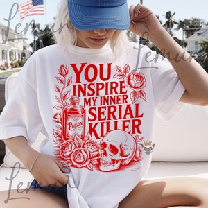 May include: White t-shirt with a red graphic that reads "YOU INSPIRE MY INNER SERIAL KILLER." The design includes a poison bottle, roses, and a skull. The shirt is a casual, oversized fit.