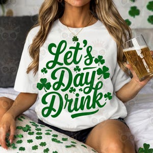 Może przedstawiać: Biała koszulka z zielonymi wzorami koniczyny i tekstem "Let's Day Drink".