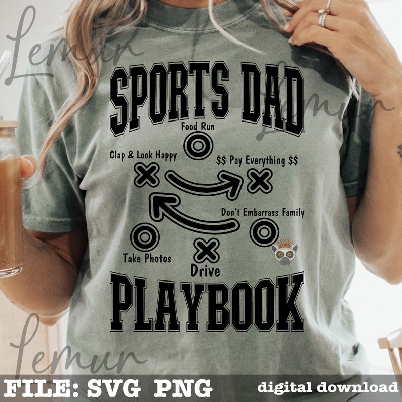 以下が含まれることがあります： 「SPORTS DAD PLAYBOOK」の文字が黒い太字でプリントされた、セージグリーンのTシャツ。 「Clap & Look Happy」や「Take Photos」などの指示が書かれたプレイ図が特徴です。