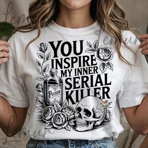 May include: White t-shirt with a black graphic design. The design includes the text "YOU INSPIRE MY INNER SERIAL KILLER", a poison bottle, roses, and a skull. The shirt is a casual wear item.