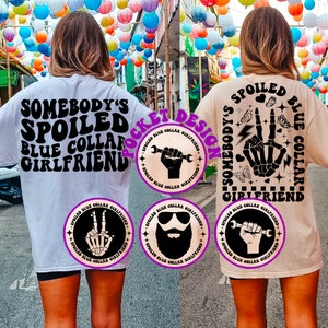 May include: Two t-shirts with a graphic design featuring the text "Somebody's Spoiled Blue Collar Girlfriend" and a variety of images including a wrench, a hand, a skull, and a beard. The text is in a retro font style.