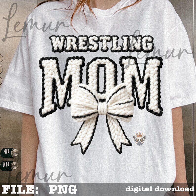May include: White t-shirt with the words "WRESTLING MOM" in a black and white knitted design. A large white bow with black trim is centered below the word "MOM". A small lemur graphic is on the right side of the shirt.