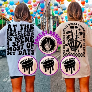 Puede incluir: Dos camisetas blancas y beige con texto negro y gráficos. La camiseta blanca dice "At the hockey rink is where I spend most of my days" y tiene un gráfico de disco de hockey negro. La camiseta beige dice "At the hockey rink is where I spend most of my days" y tiene un gráfico de mano de esqueleto negro. Ambas camisetas tienen un gráfico de disco de hockey negro con las palabras "Hockey Mom", "Hockey Season" y "Hockey Mama" en ellas.