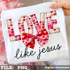 Könnte beinhalten: Weißes T-Shirt mit dem Wort "LOVE" in einem Patchwork-Design mit roten und rosa Herzen. Eine rote Schleife mit Herzmustern befindet sich unter dem Wort "LOVE". Der Satz "like jesus" ist in schwarzer Schrift unter der Schleife geschrieben.