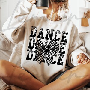 May include: A white sweatshirt with a black and white chequered bow and the text "DANCE DANCE DANCE" printed on it.