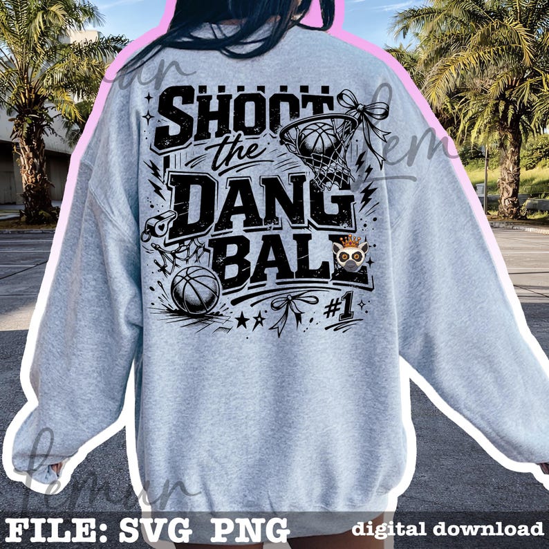 Puede incluir: Sudadera gris claro con un dise&ntilde;o de baloncesto. El dise&ntilde;o presenta el texto "SHOOT the DANG BALL" en negro, junto con balones de baloncesto, una red y un b&uacute;ho de dibujos animados con una corona. Tambi&eacute;n se incluye el n&uacute;mero "#1".