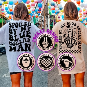May include: Two white t-shirts with black text and graphics. The front of the shirt says "Spoiled by my Blue Collar Man". The back of the shirt says "My Blue Collar Man" with a skeleton hand graphic. The pocket design on the shirt says "Spoiled by my Blue Collar Man" with a skeleton hand graphic.