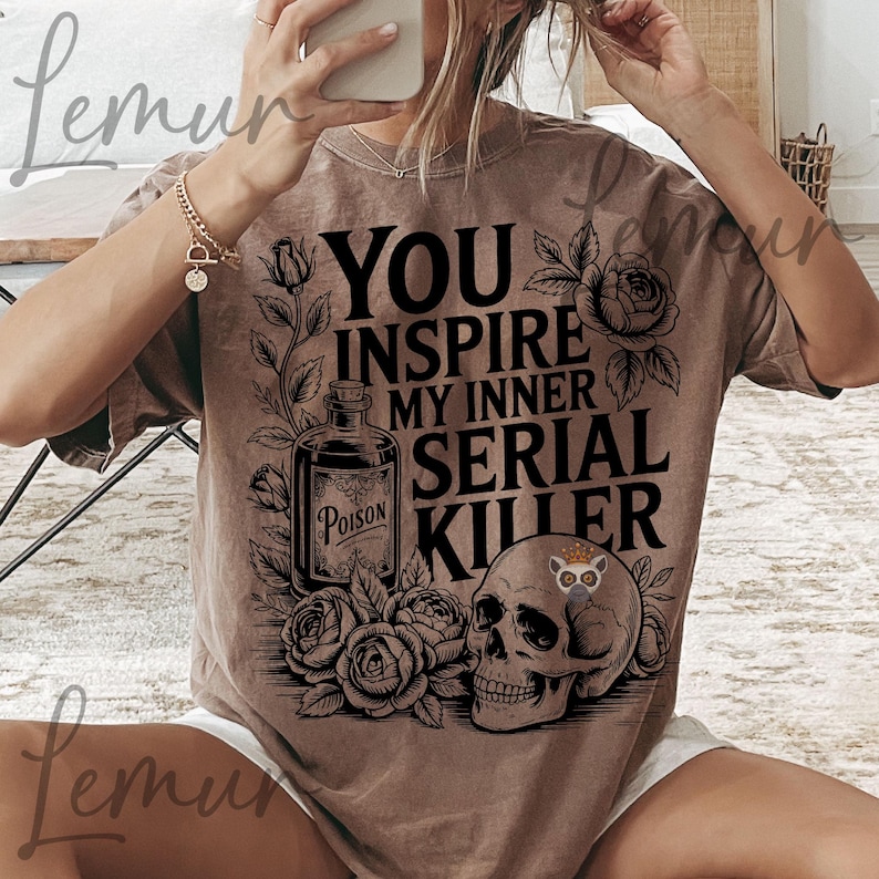 May include: Brown t-shirt with the text "YOU INSPIRE MY INNER SERIAL KILLER" in black. The graphic includes a poison bottle, roses, and a skull with a small animal on it. The shirt has a vintage, distressed look.