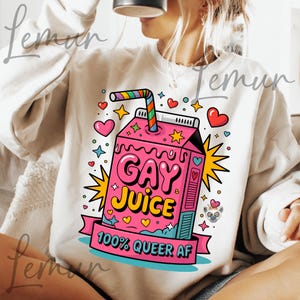 Puede incluir: Sudadera beige claro con un diseño de caja de jugo rosa. El diseño dice "GAY JUICE" y "100% QUEER AF" con corazones, estrellas y una pajita arcoíris. El diseño es de estilo caricatura.