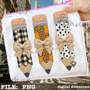 May include: A white fabric surface featuring three pencil-shaped applique designs. Each pencil has a quilted tan eraser, a grey band, a beige linen bow, and a wood-textured tip. The pencil bodies feature black plaid, leopard print, and black polka dots.