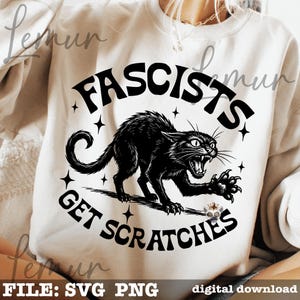 May include: Cream-colored sweatshirt featuring a black graphic of an angry cat with the text "Fascists Get Scratches." The design includes star accents and is a digital download.