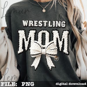 May include: Dark gray sweatshirt with the words "WRESTLING MOM" in white, outlined in black, with a white bow in the center. The sweatshirt has a digital download file type.
