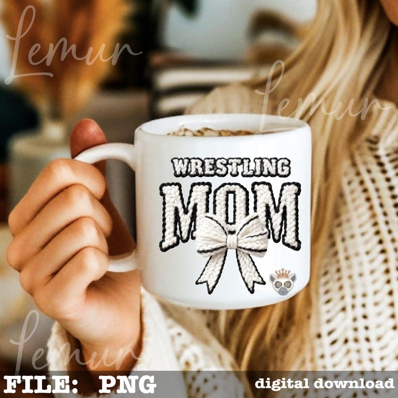 May include: White ceramic mug with the words "WRESTLING MOM" in black and white, featuring a bow graphic. The mug is held by a person.