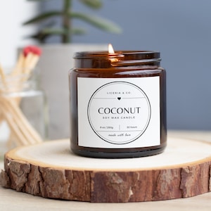 Peut inclure: Une bougie en verre brun dans un bocal avec une étiquette blanche sur laquelle est inscrit "Liceria & Co." et "Coconut Soy Wax Candle". L'étiquette indique également les détails "8 oz / 230g" et "30 heures".