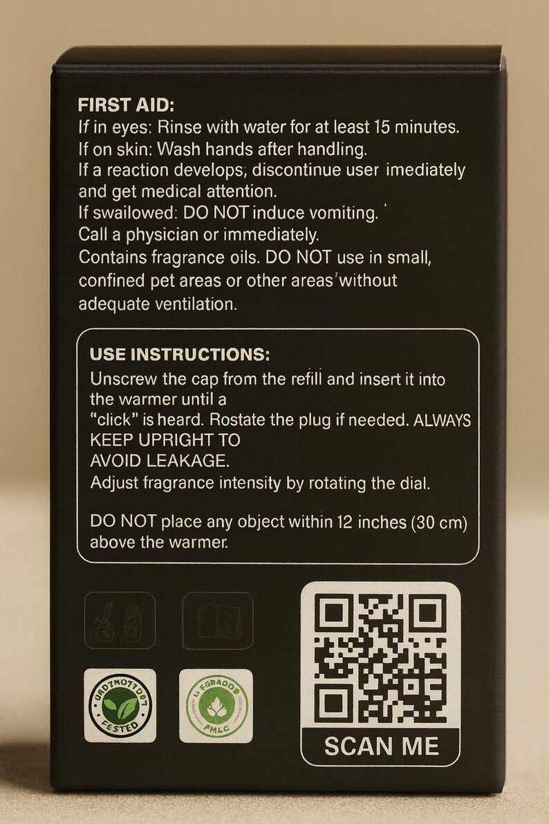 May include: Black box with white text detailing first aid, use instructions, and safety warnings for fragrance oils. Includes a QR code labeled "SCAN ME" and two product certification logos. The text advises against placing objects within 12 inches (30 cm) of the warmer.