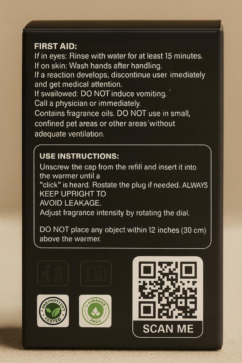 May include: Black box with white text detailing first aid, use instructions, and safety warnings for fragrance oils. Includes a QR code labeled "SCAN ME" and two product certification logos. The box warns against placing objects within 12 inches of the warmer.