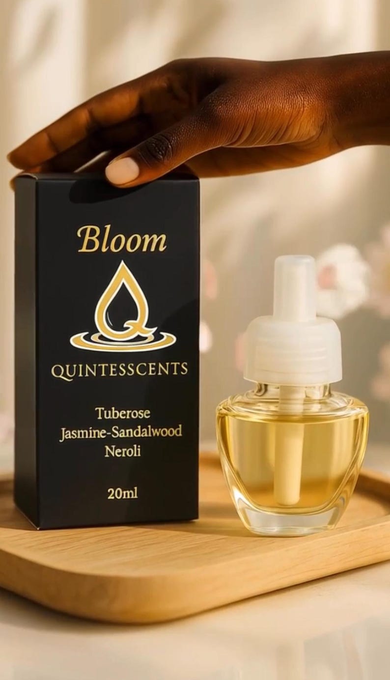 May include: A black box and a clear glass air freshener with a white top. The box reads "Bloom QUINTESSCENTS" with the scent notes: Tuberose, Jasmine-Sandalwood, Neroli. The air freshener contains 20ml of liquid.