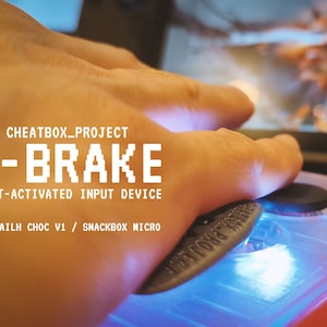 以下が含まれることがあります： Kailh Choc V1 / Snackbox Micro 用の「D-BRAKE」と呼ばれる青と白の腕で操作する入力デバイスのクローズアップ。デバイスは赤い表面の上で手で操作されています。