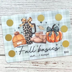 May include: A gift card with a plaid background featuring fall-themed illustrations. The card includes a beanie, boots, a pumpkin, and a leopard print tumbler. The text "Fall basics" and "stuff and budget" are also present.