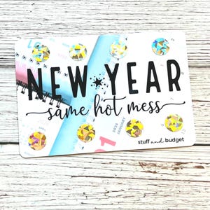 May include: A white rectangular card with the text "NEW YEAR same hot mess" in black script. The card has a calendar design with colorful gems and the words "stuff and budget".