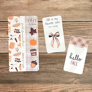 May include: Three decorative cards with fall-themed designs. One card features the text "Fall is here" with a pumpkin, leaf, and coffee cup. Another says "Fall is my favorite color" with a bow. The third says "hello FALL".