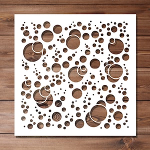 May include: White stencil with a design of various sized circles, some overlapping, creating a pattern of bubbles.