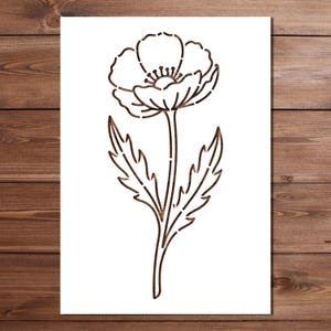 May include: A brown wooden cutout of a poppy flower with detailed petals, stem, and leaves. The flower is centered on a white background, with a wooden plank backdrop.