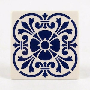 Könnte beinhalten: Eine quadratische Keramikfliese mit einem dunkelblauen, symmetrischen Blumenmuster auf cremefarbenem Hintergrund. Das Design besteht aus einem zentralen kreisförmigen Motiv, das von vier stilisierten blattartigen Formen und geschwungenen Linien umgeben ist.