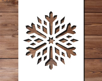 May include: A white paper snowflake cutout with a detailed design, against a wood background.