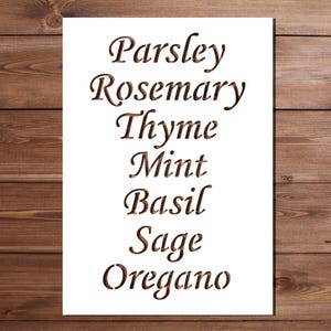 May include: A rectangular white stencil featuring seven laser-cut herb names in a vertical list: Parsley, Rosemary, Thyme, Mint, Basil, Sage, and Oregano. The lettering is in a classic serif font, with the wood grain visible through the cutouts.