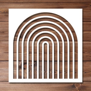 Puede incluir: Diseño de corte blanco de un arcoíris con múltiples capas. El diseño está sobre un fondo de madera.
