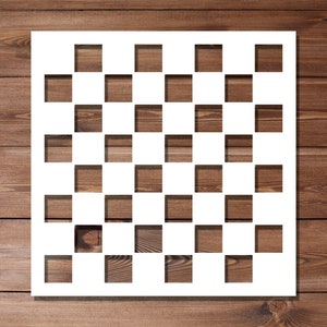 May include: White stencil with a checkerboard pattern of 6 rows and 8 columns of squares. The stencil is on a brown wooden background.