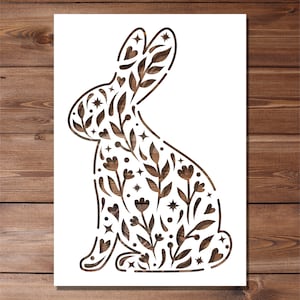 May include: A white silhouette of a rabbit with a floral pattern inside. The rabbit is sitting with its ears up and its tail behind it.