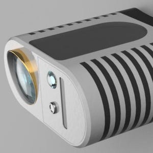 Op de afbeelding: Een moderne, compacte projector met een wit en zwart ontwerp. De lens heeft een goudkleurige rand. De behuizing heeft zwarte verticale strepen aan één kant en een zwart bovenpaneel. Twee knoppen en een klein indicatielampje zijn zichtbaar aan de voorkant.