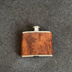 May include: A silver and wood flask with a wood grain pattern.
