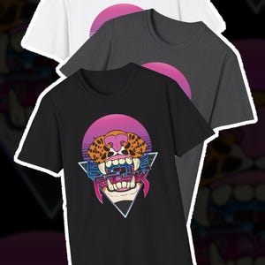 May include: Three short-sleeve t-shirts in white, charcoal gray, and black. Each shirt features a graphic of a leopard face with bared teeth, a pink sun, and a blue triangle. The text "BATTLE RISK" is printed in blue over the leopard's mouth.