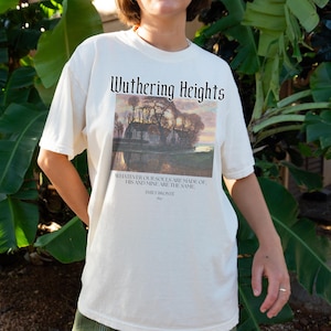 May include: A white t-shirt with a black graphic print of a house and trees reflected in a lake. The text "Wuthering Heights" is printed above the image and a quote from Emily Bront&euml; is printed below the image.