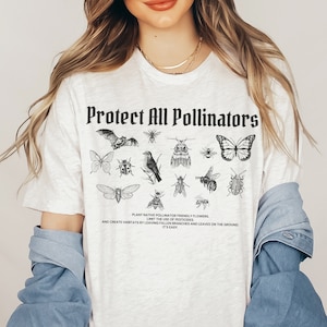 May include: White t-shirt with the text "Protect All Pollinators" in black bold letters. The shirt features a variety of black and white illustrations of pollinators, including a bat, a bird, a butterfly, and various insects.