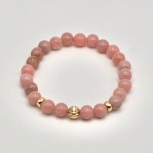 May include: A pink opal beaded bracelet with a gold accent bead.