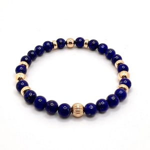Op de afbeelding: Een blauwe en gouden kralen armband met een gouden accent kraal. De armband is gemaakt van lapis lazuli en gouden kralen.