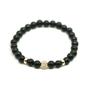 May include: A black beaded bracelet with a gold bead accent.