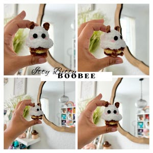 May include: Four images of a small, white, plush toy shaped like a bear with black eyes and a brown nose. The bear is holding a small, brown, cupcake with white frosting. The text "Itty Bitty Boobee" is visible in the image.